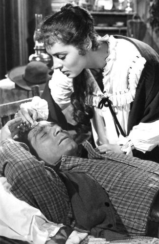 Viveca Lindfors as Elena de Ortega nurses Richard Conte as Jan Morrell in The Raiders (1952)