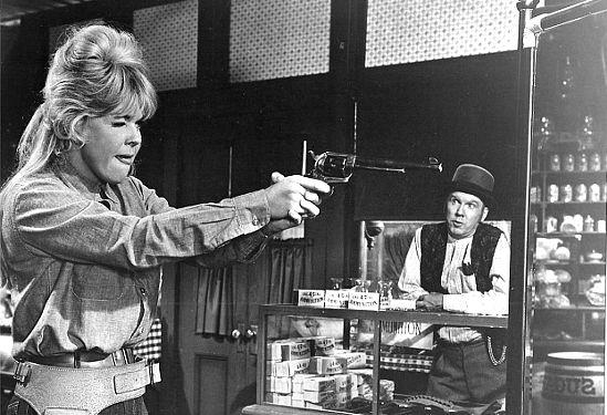 Doris Day as Josie Minick practices her six-gun skills as shopkeeper Simpson (John Fiedler) looks on in The Ballad of Josie (1967)