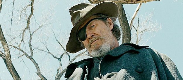 Jeff Bridges as Rooster Cogburn, examining a hanged man to see if it's someone he knows in True Grit (2010)