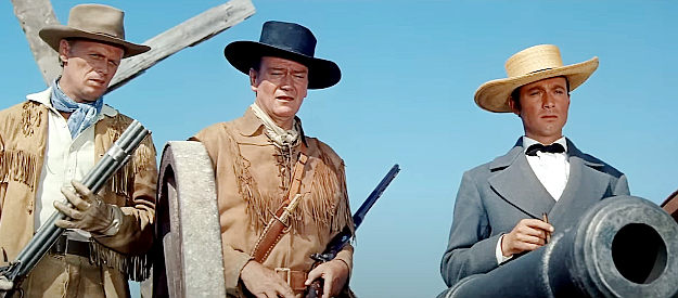 Laurence Harvey as Col.. William Travis prepares to answer a surrender demand with a blast from a cannon as Jim Bowie (Richard Widmark) and Davy Crockett (John Wayne) look on in The Alamo (1960)
