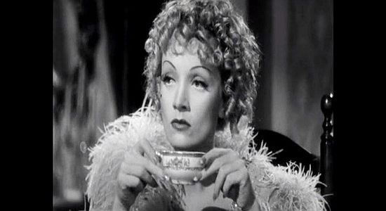 Marlene Dietrich as Frency, grudingly listening to Destry's questions about a former sheriff over a cup of tea in Destry Rides Again (1939)