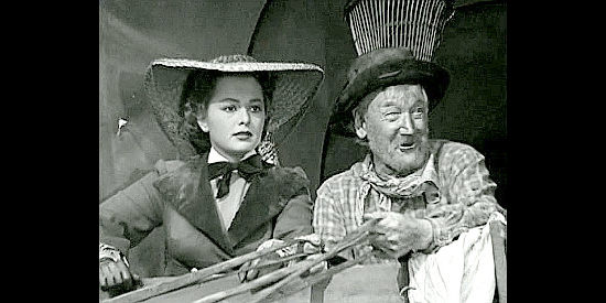 Olivia de Havilland as Elizabeth Bacon,arriving at a post out West with California Joe (Charley Grapewin) in They Died With Their Boots On (1941)