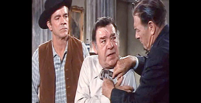 Dana Andrews as Tom Rosser watches Dr. Kent (Richard Arlen) work on a wound suffered by Mayor Charlie Leach (Lon Chaney Jr.) in Town Tamer (1965)