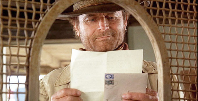 Terence Hill as Doc West, getting a letter from the young girl he's putting through school in Triggerman (2009)