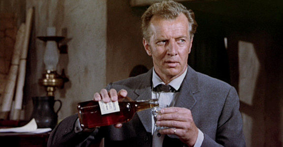 Bruce Bennett as Commissioner Harrison, the carpetbagger with his eyes on the Saunders ranch in Three Violent People (1957)