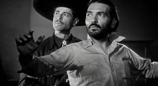 Carlos Muzquiz as Col. Sanchez with blacksmith Enrique Ortiz (Jose Torvay) under his gun in My Outlaw Brother (1951)