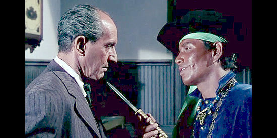 Jay Silverheels as Yaqui, holding a bank manager at knife point during a holdup in Four Guns to the Border (1954)
