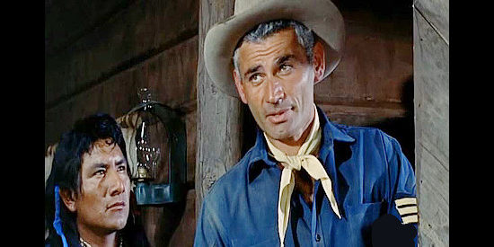 Jeff Chandler as 1st Sgt. Emmett Bell, offering his advice for dealing with the Indians while Lucas (Felix Noriega), one of his scouts, looks on in Pillars of the Sky (1956)