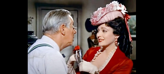 Linda Darnell as Amy Clarke, charming ticket agent Tully Morgan (Irving Bacon) into swapping a stage ticket for a garter in Dakota Incident (1956)