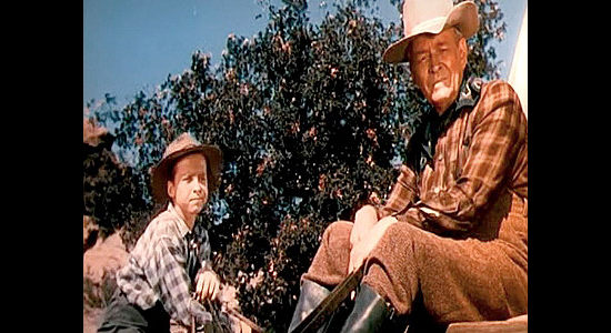 Michael Chapin as Ben Wilkins and Wheaton Chambers as his father Sam, watching Ann ride down a hillside with Jeff Curtis in Wagons West (1952)