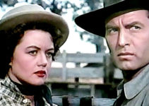 Dorothy Malone as Charlotte Downing and George Montgomery as Cruze, realizing they have a common goal in The Lone Gun (1954)