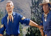 Jeff Chandler as 1st Sgt. Emmett Bell and Sydney Chaplin as Timothy, one of his scouts, watching a war party approach in Pillars of the Sky (1956)