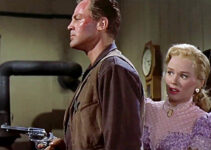 John Agar as Sheriff Bill Jordan, ready for any unexpected visitor to his office while fiancee Ellen Ballard (Mamie Van Doren) hides behind him in Star in the Dust (1956)