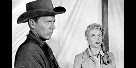 Peter Graves as Sawyer, a man with a saddlebag full of secrets, with Kate Bolden (Peggie Castle) looking on in The Yellow Tomahawk (1952)
