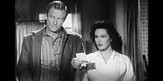 Richard Denning as Dr. Bruce Merritt and Patricia Medina as Angela Medley with the ad her father used to sell his doctor's practice in The Buckskin Lady (1957)