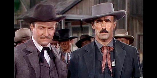 Robert Douglas as Aubrey Milburn and John Halloran as the sheriff, trying to figure out why Judith Burns looks so much like the woman on a wanted poster in Barricade (1950)