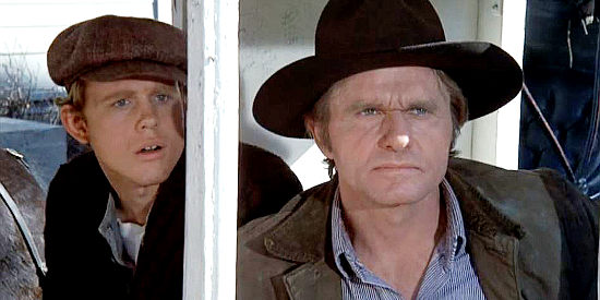Bill McKinney as Jay Cobb, reacting rudely to J.B. Brooks as Gillom Rogers (Ron Howard) looks on in The Shootist (1976)
