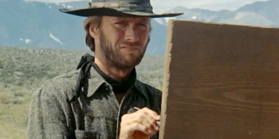Clint Eastwood as The Stranger, making alterations to the sign welcoming people to Lago in High Plains Drifter (1973)