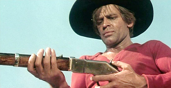 Klaus Kinski as Gary Hamilton, examining his weapon of vengeance in And God Said to Cain (1970)