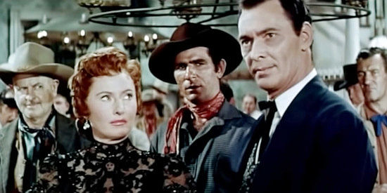 Barbara Stanwyck as Kit Banion, watching Jeff Younger (Barry Sullivan) settle a gambling dispute in her saloon in The Maverick Queen (1956)