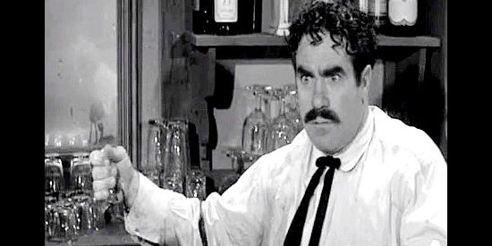 Candy Candido as the bartender, holding the evidence of Clint Jones' six-gun skills in Plunderers of Painted Flats (1958)