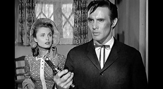 James Mitchell as Parson Butler, weighing a gun against his Bible as Ann Davis (Rosemarie Bowe) looks on in The Peacemaker (1956)