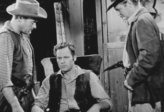 John Agar as Jeff Donner, being questioned by Samuel (Richard Shannon) and Dory (Charles Gray), Rebel agents in Ride a Violent Mile (1957)