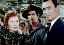 Barbara Stanwyck as Kit Banion, watching Jeff Younger (Barry Sullivan) settle a gambling dispute in her saloon in The Maverick Queen (1956)