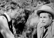 Buster Crabbe (right) as Linc Prescott, coming to the aid of a wounded Brother Van (John Smith) in The Lawless Eighties (1957)