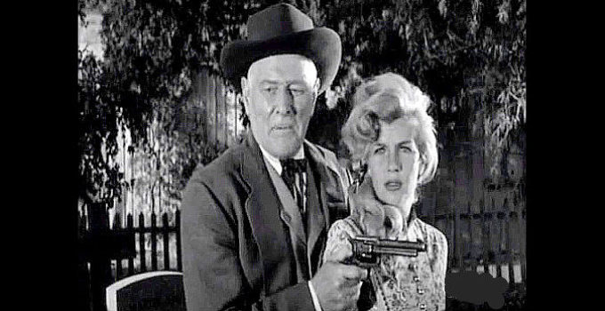 Corinne Calvet as Kathy Martin under the gun of Ed Sampson (George Macready) in Plunderers of Painted Flats (1959)