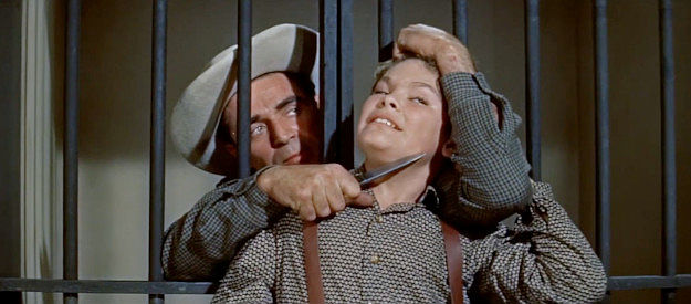 Steve Cochran as Mike Davis, holding a knife to the throad of Joel (Kim Charney) to escape jail in Quantrill's Raiders (1958)