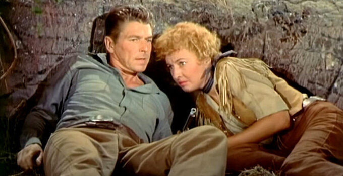 Ronald Reagan as Farrell and Barbara Stanwyck as Sierra Nevada Jones, taking cover from the Indians in Cattle Queen of Montana (1954)