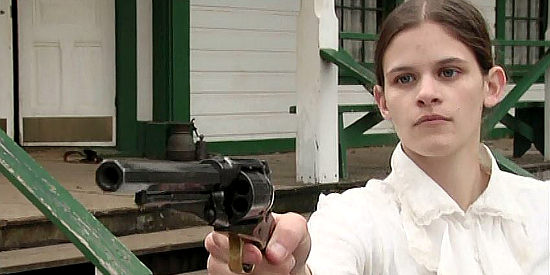Judy Rhodes as the Niece, brandishing a pistol to defend the boarding house where she finds refuge in Living by the Gun (2011)