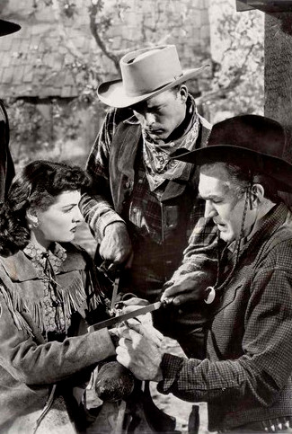 Scott Brady as Bbo Dalton (standing) and Forrest Tucker as Mac work to get Jane Russell's Belle Starr out of handcuffs in Montana Belle (1952)