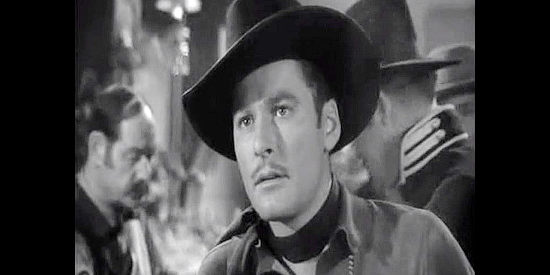 Errol Flynn as Kerry Bradford, surprised to spot new acquaintance Julia Hayne on a saloon stage in Virginia City (1940)