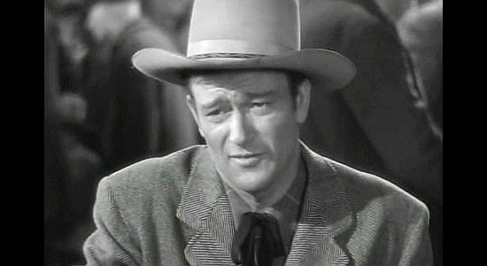 John Wayne as Roy Glennister, trying to charm his way back into Cherry Malotte's good graces in The Spoilers (1942)