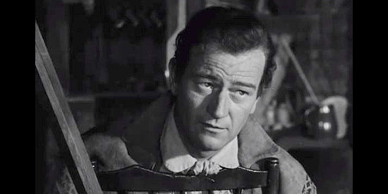 John Wayne as John Breen, hearing details about how the French have been tricked into settling on the wrong land in The Fighting Kentuckian (1949)