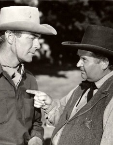 Randolph Scott as Brazos Kane listens to Charles Kemper as Sheriff ...