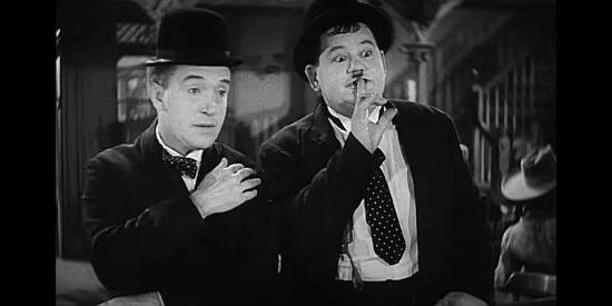Stan Laurel and Oliver Hardy, about to spill what's supposed to be a secret in Way Out West (1937)