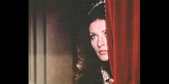 Malisa Longo as Jenny McKinley, peeking at a barroom brawl from behind a curtain in And Now They Call Him Sacramento (1972)