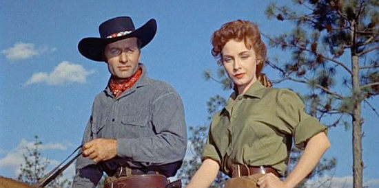 George Montgomery as 'Tex' and Sylvia Findley as Helen Herrick survey her crippled brother's herd in Robbers' Roost (1955)