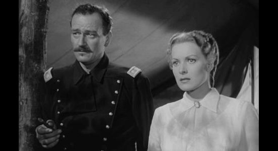 John Wayne as Lt. Col. Kirby Yorke and Maureen O'Hara as his estranged wife Kathleen, listening to a performance by the regimental singers in Rio Grande (1950)