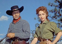 George Montgomery as 'Tex' and Sylvia Findley as Helen Herrick survey her crippled brother's herd in Robbers' Roost (1955)