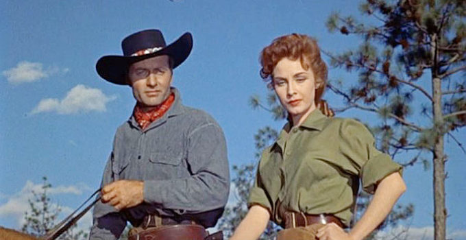 George Montgomery as 'Tex' and Sylvia Findley as Helen Herrick survey her crippled brother's herd in Robbers' Roost (1955)