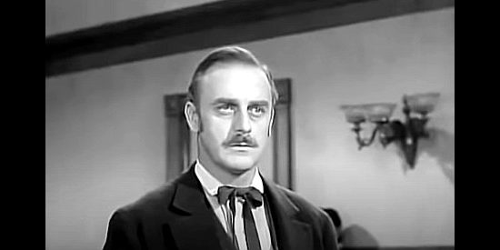 John Dehner as Roger Pollock, the high-priced attorney hired by the sheriff to defend Benjie in The Iron Sheriff