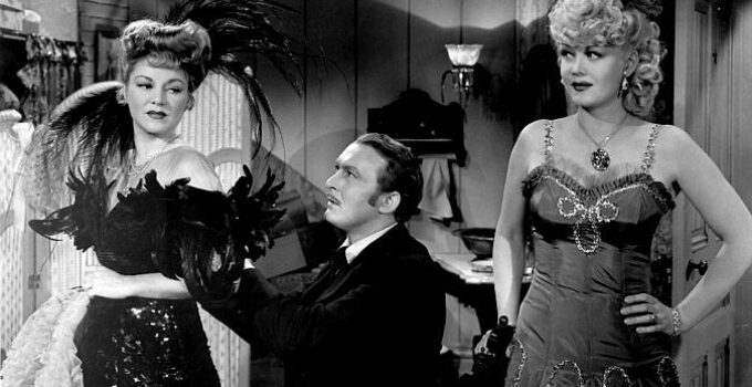 Claire Trevor as Dora Hand commanding the attention of Bat Masterson (Albert Dekker) to the dismay of Daisy Davenport (Marion Martin) in Woman of the Town (1943)