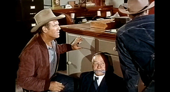 Roy Barcroft as outlaw Curt Walker, waiting with tied up banker Mr. Potter (Paul E. Burns) for the safe to blow in Oklahoma Annie (1952)