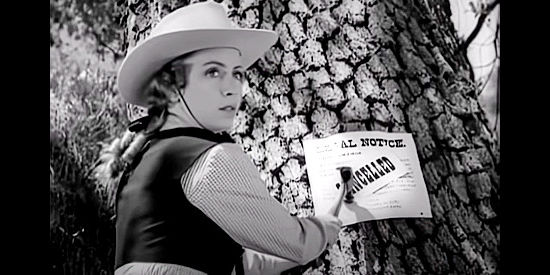 Barbra Fuller as Louise Cole, altering one of the signs Wade Proctor has posted in The Savage Horde (1950)