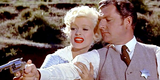 Kenneth Moore as Jonathan Tibbs distracted during a shooting lesson with Jayne Mansfield as Kate in The Sheriff of Fractured Jaw (1958)