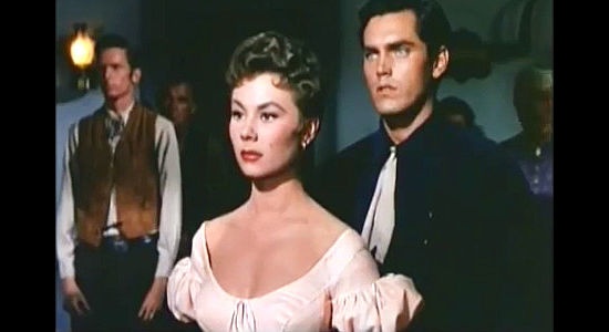 Mitzi Gaynor as Rusty Blair and Jeffrey Hunter as Johnny Colt, listening to the sheriff announce the train holdup in Three Young Texans (1954)